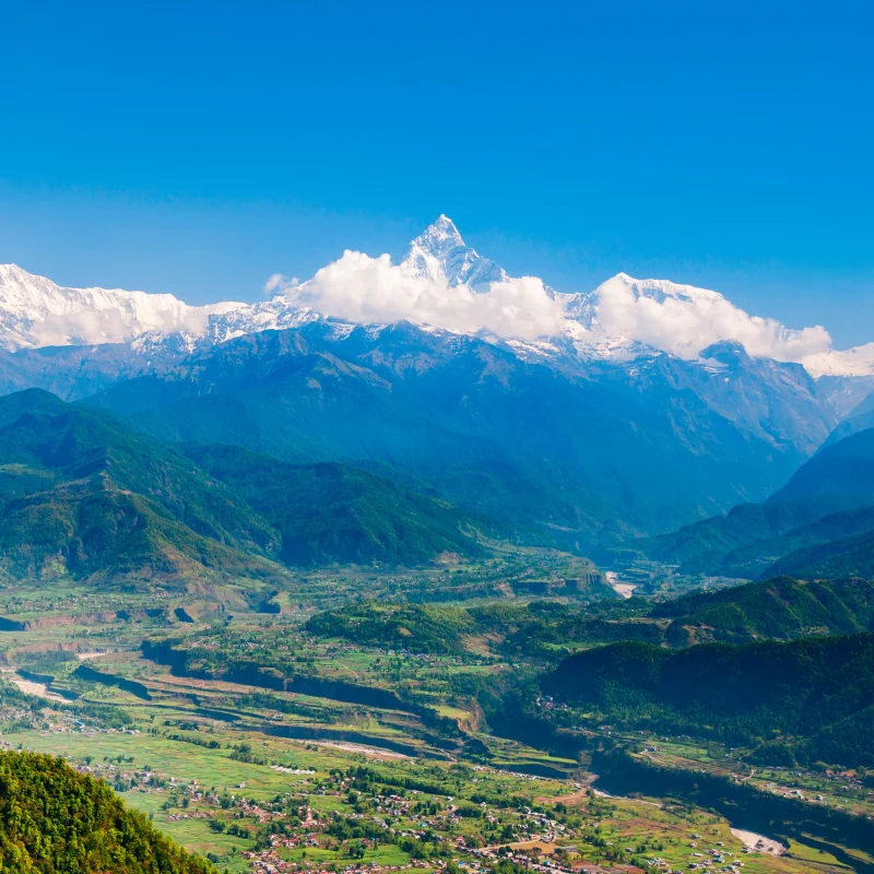High-angle aerial view of green Pokhara valley settlements with the iconic Machhapuchhre Fishtail peak rising in the Annapurna range Nepal.