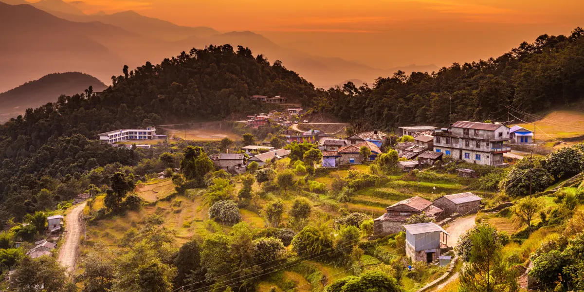 Golden sunset light shining over terraced farmlands and hillside lodges in Chistibung village on the Khopra Danda trek Nepal.